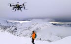This Dec. 2014 photo shows a drone hovering by a skier as he makes his way down mountainside at resort at Revelstoke, B.C., Canada. Some US ski resort