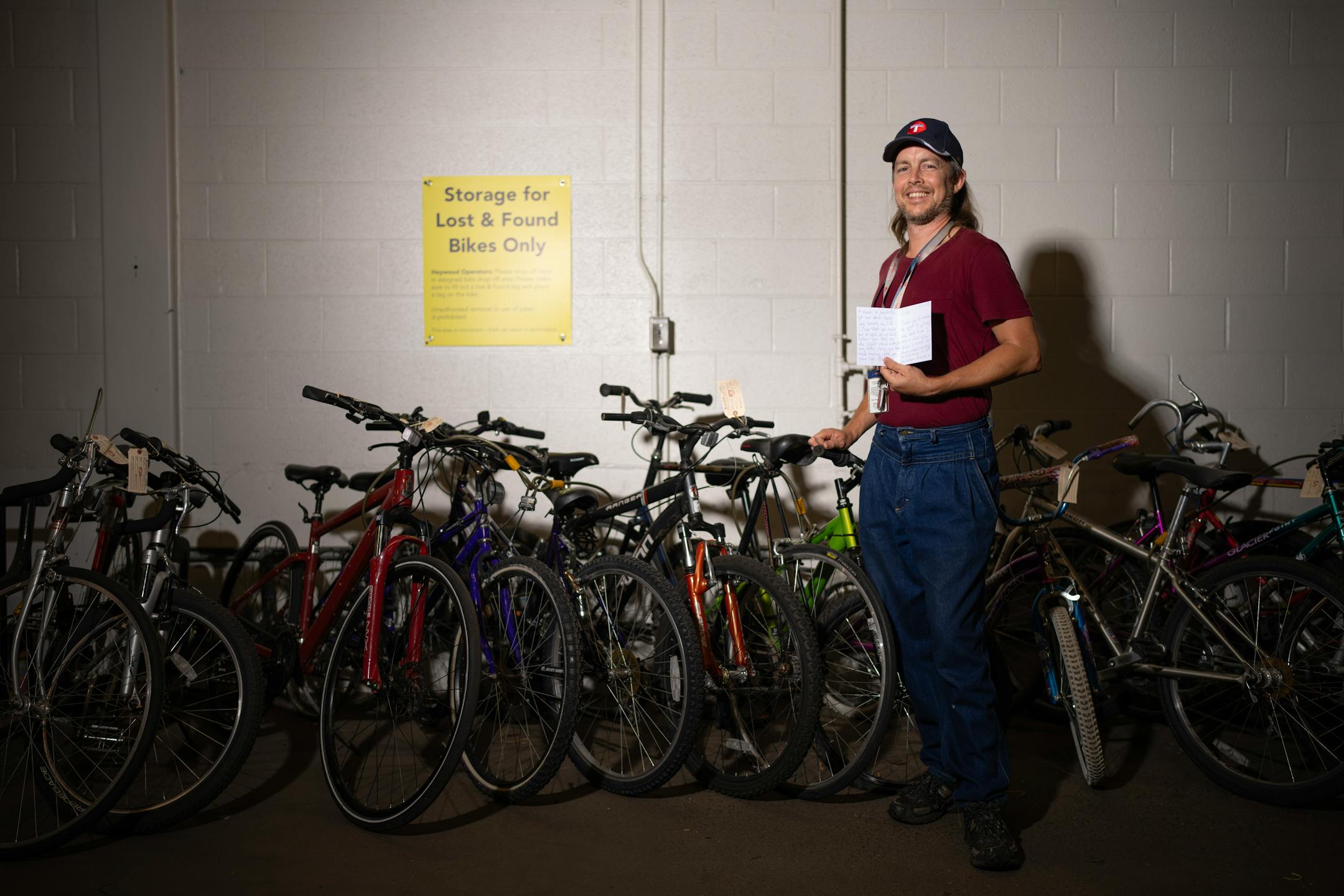 Metro Transit Customer Service staffer Nicholas Heimer with the thank you card he got last week from a woman who he was able to reunite with her bicycle, in the bicycle storage area at Metro Transit headquarters in Minneapolis. The lost and found room contains bins with lots of phones and keys and many, many other types of objects.