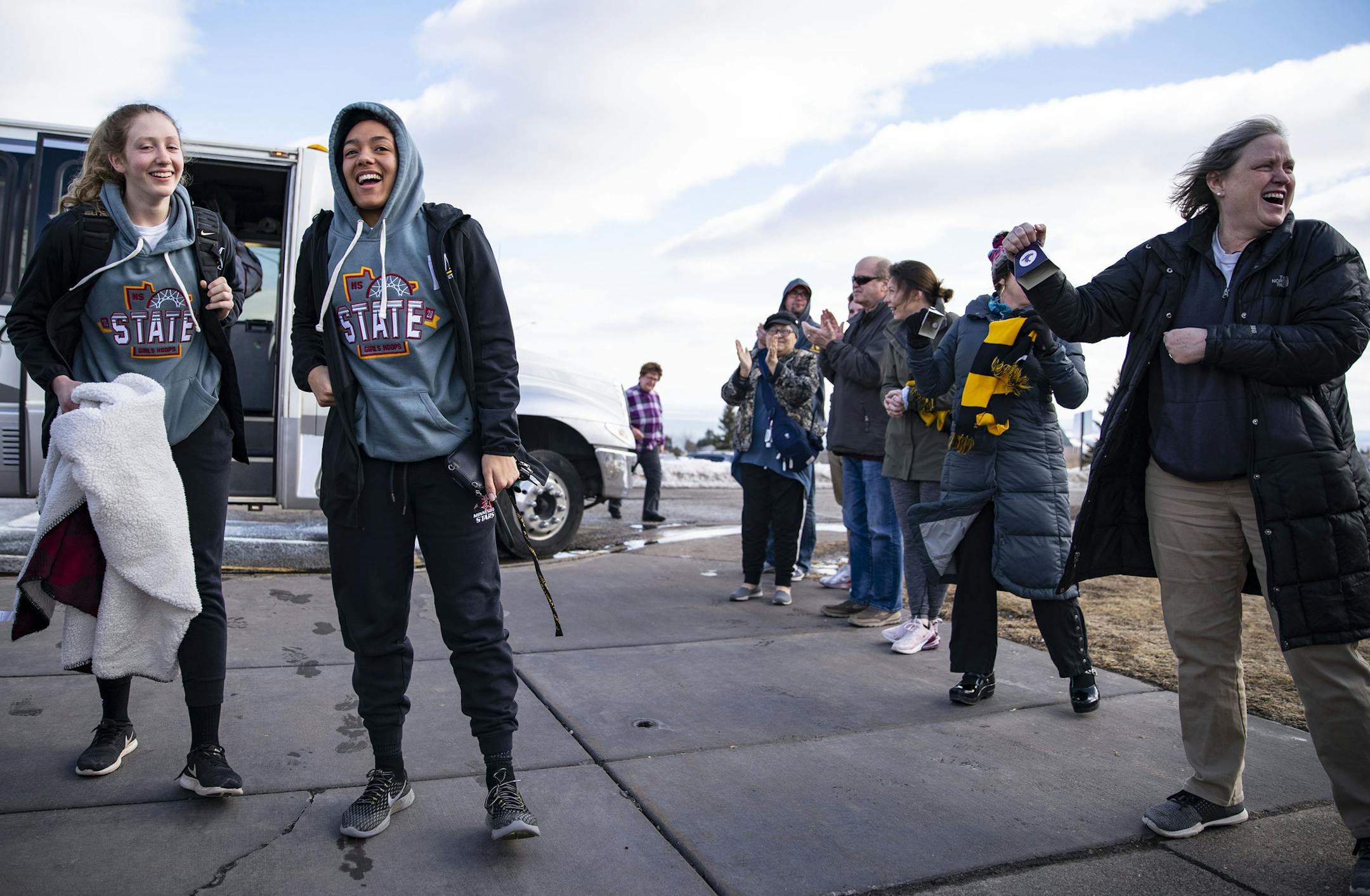 The Duluth Marshall girls' basketball team exited their bus to a line of applauding parents in the parking lot of their school after driving back from Minneapolis on Friday