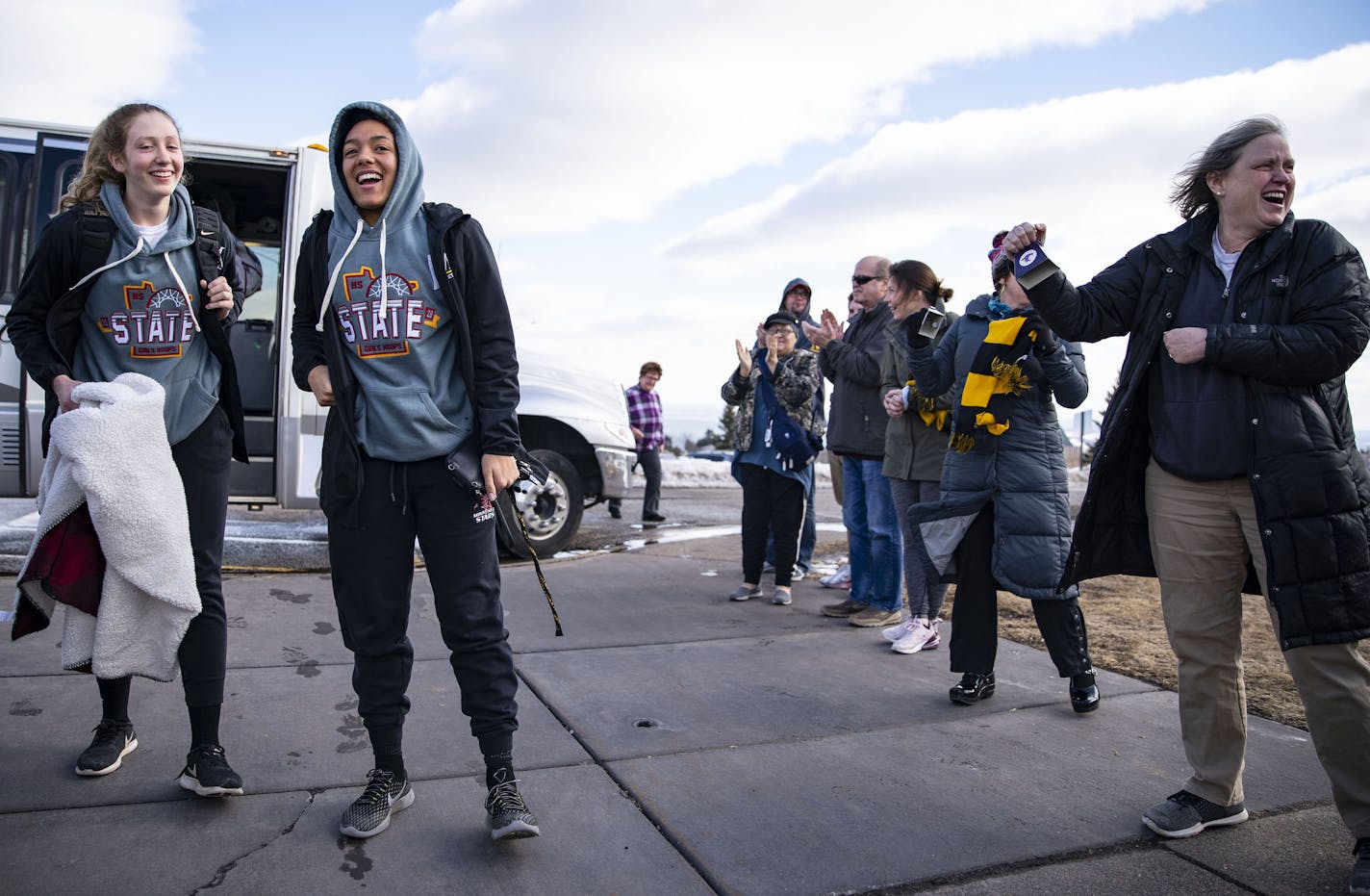 The Duluth Marshall girls' basketball team exited their bus to a line of applauding parents in the parking lot of their school after driving back from Minneapolis on Friday