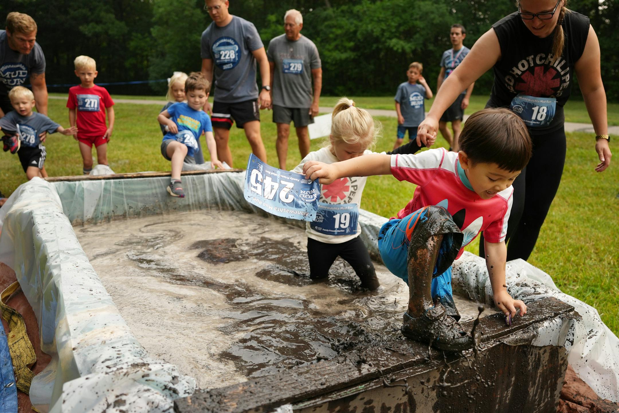 Noah Strandberg, 4, of Minnetonka carries his bib as he wades through a mud pit.