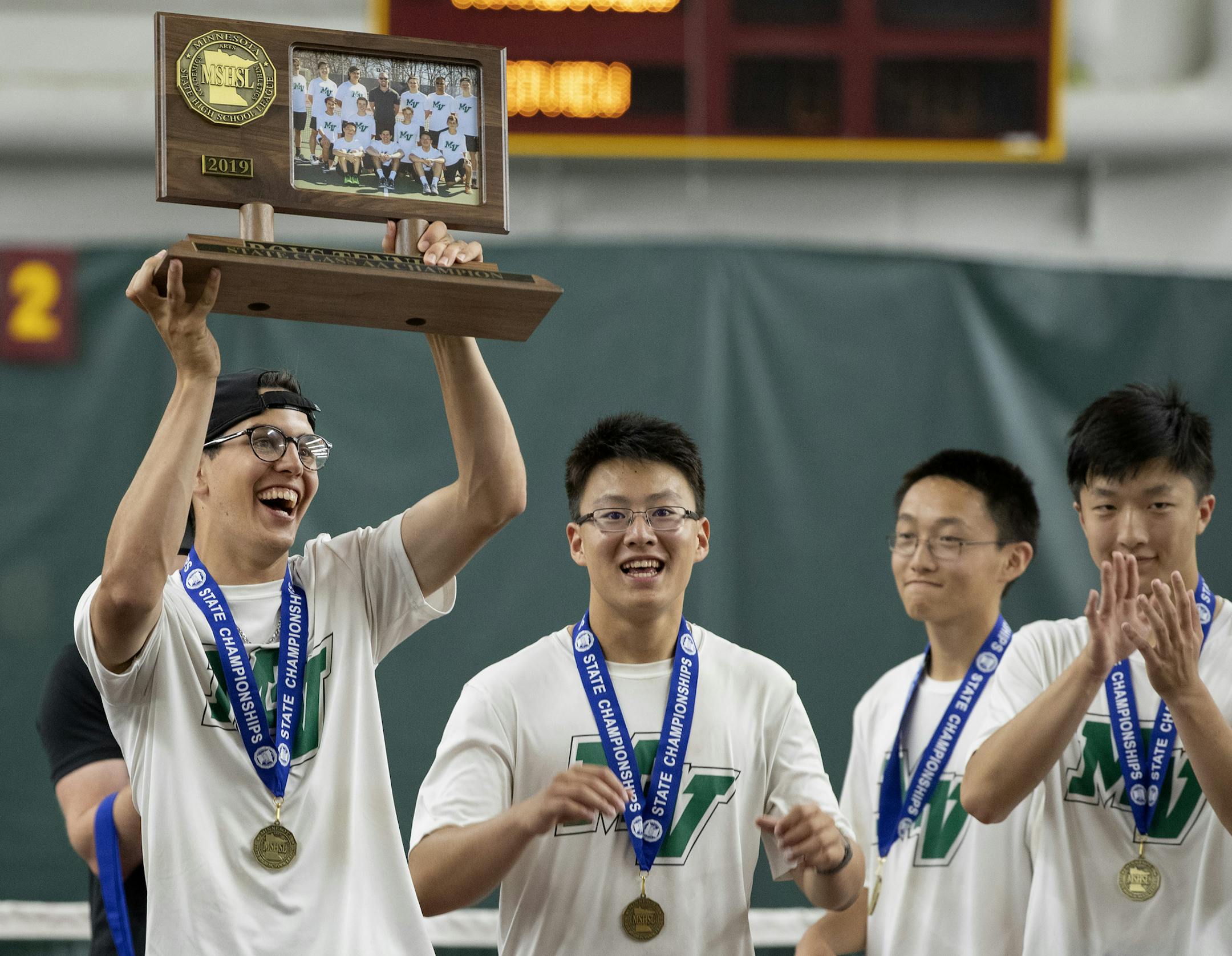 Petro Alex held the team championship trophy as teammates from Mounds View celebrated. ] CARLOS GONZALEZ • cgonzalez@startribune.com – Minneapolis, MN – June 5, 2019, Baseline Tennis Center, University of Minnesota, High School / Prep 2A boys' tennis team championship. Mounds View vs. Eastview