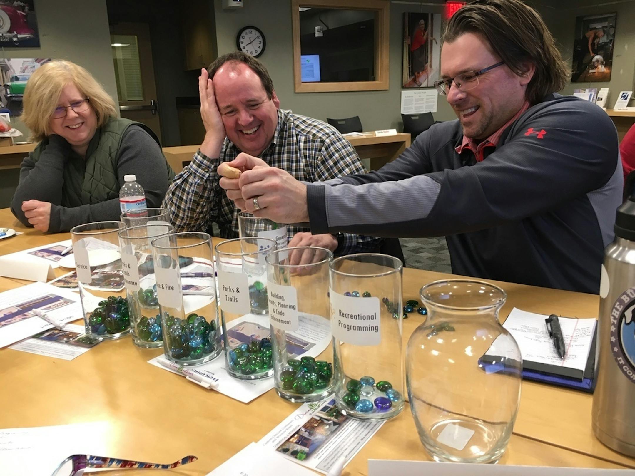 Using marbles and jars, Victoria residents Sheila Butler, Jerret Coon and Christian Pederson practiced distributing budget items in Victoria's Citizens Academy.
