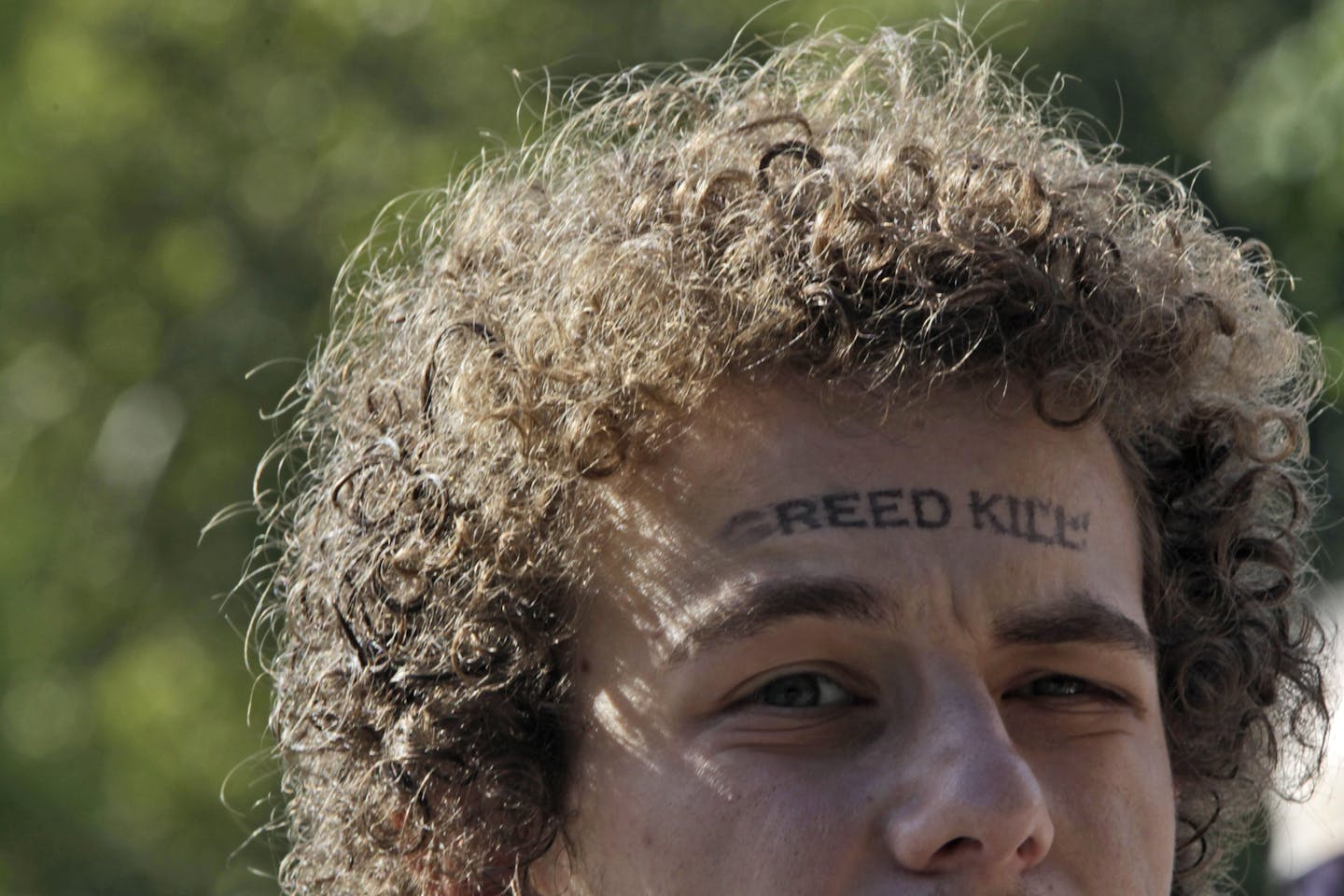 An activist associated with the Occupy Wall Street movement has the words "Greed Kill" stamped on his forehead during a gathering of the movement in Washington Square park, Saturday, Sept. 15, 2012 in New York. T