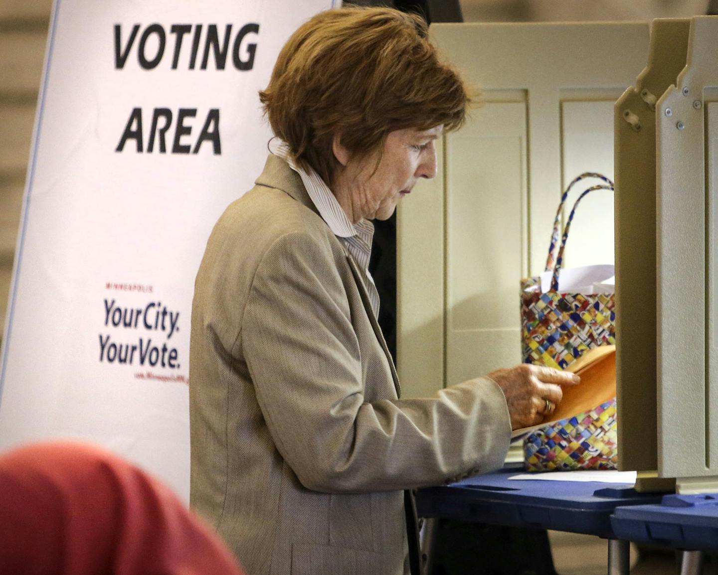 Jane Mauer of Minneapolis, who will be out of town on voting day, places her ballot in an envelope after completing her first absentee ballot ever at the Minneapolis City Hall Friday, Aug. 8, 2014, in Minneapolis, MN.] (DAVID JOLES/STARTRIBUNE) djoles@startribune A heated primaries have drawn an outpouring of absentee ballots in the first race where voters are being encouraged to vote early through the new no excuses absentee rules.**Jane Mauer,cq ORG XMIT: MIN1408081903364263