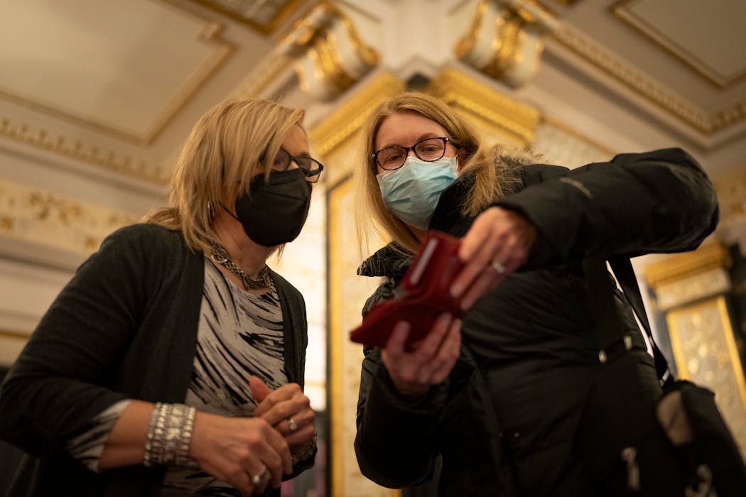 Gail Nelson of the Hennepin Theatre Trust, left, checked the vaccination status of a patron in the lobby of the State Theatre in January. The State, Orpheum and Pantages theaters in Minneapolis all still require masks and proof of vaccine or a negative COVID test. 