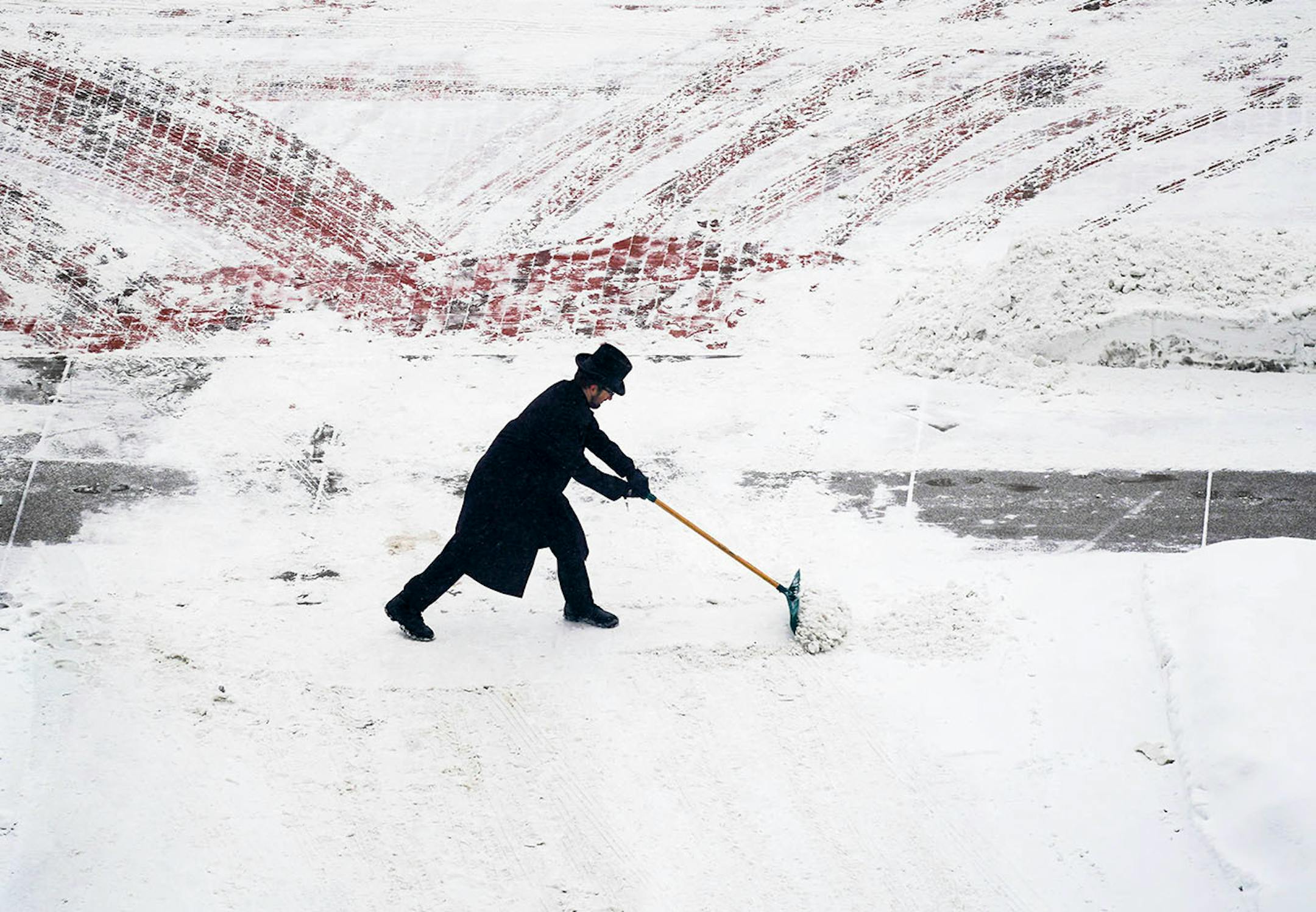 Saint Paul Hotel doorman Tyson Heinz struggled to keep the hotel driveway clear as snow continued Sunday morning.