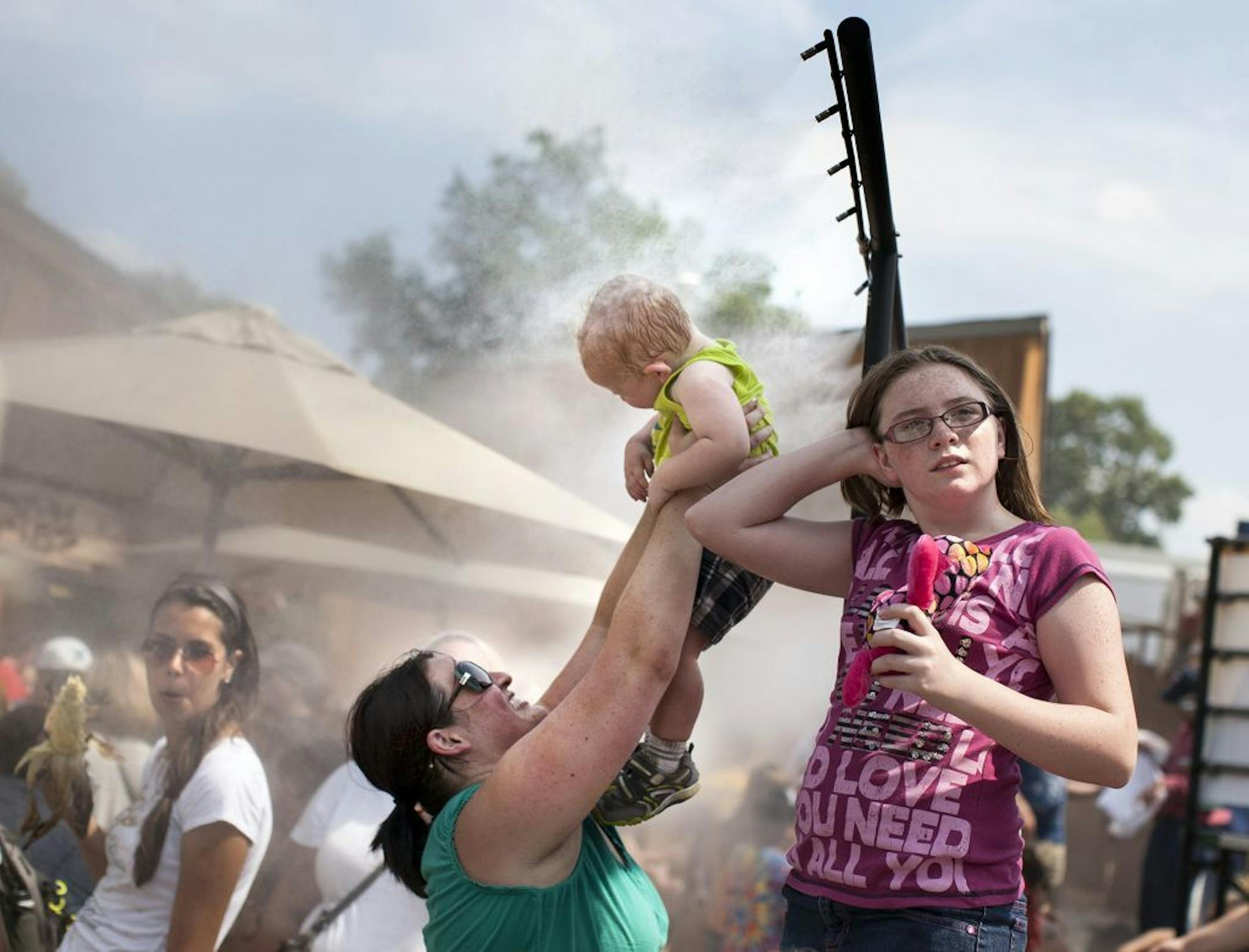 Sarah Roy of Maplewood holds up her 1-year-old son, Mikey Roy, to the misters on a hot day at the Minnesota State Fair August 24, 2013.