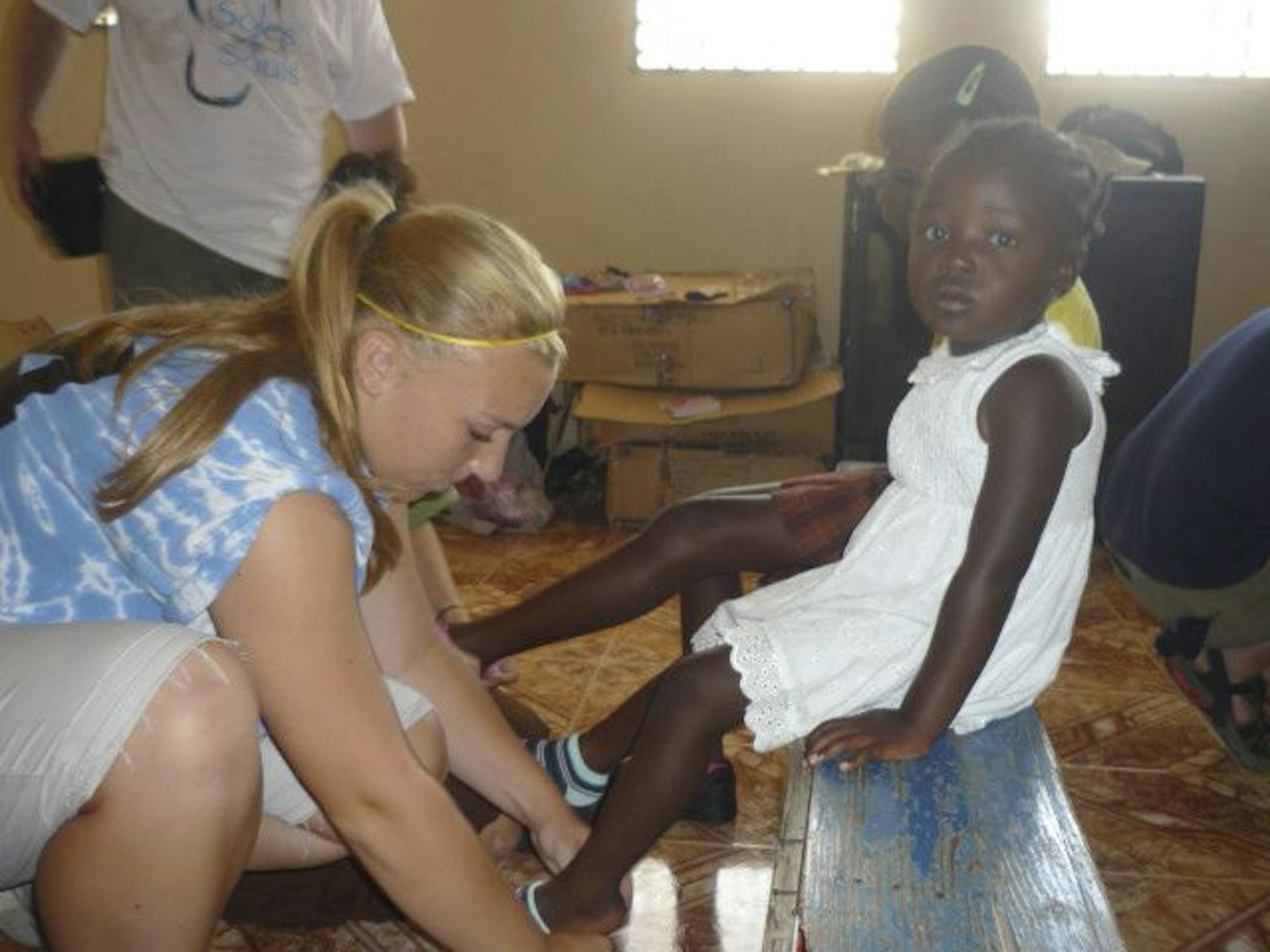 Provided by Claire Frances Baker"The Shoe Collector" Claire Frances Baker putting shoes on a girl during her trip to Haiti.