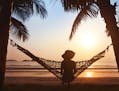 woman relaxing in hammock at sunset on the beach. istock