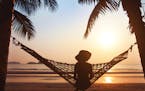 woman relaxing in hammock at sunset on the beach. istock