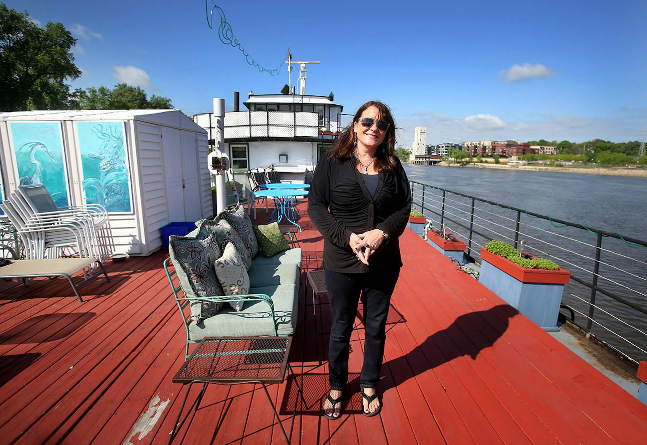 Innkeeper Liz Miller on the deck of The Covington Inn, a floating B&B anchored on Harriet Island. The B&B, which includes four bedroom suites and innkeeper's quarters, is for sale for $529,900.