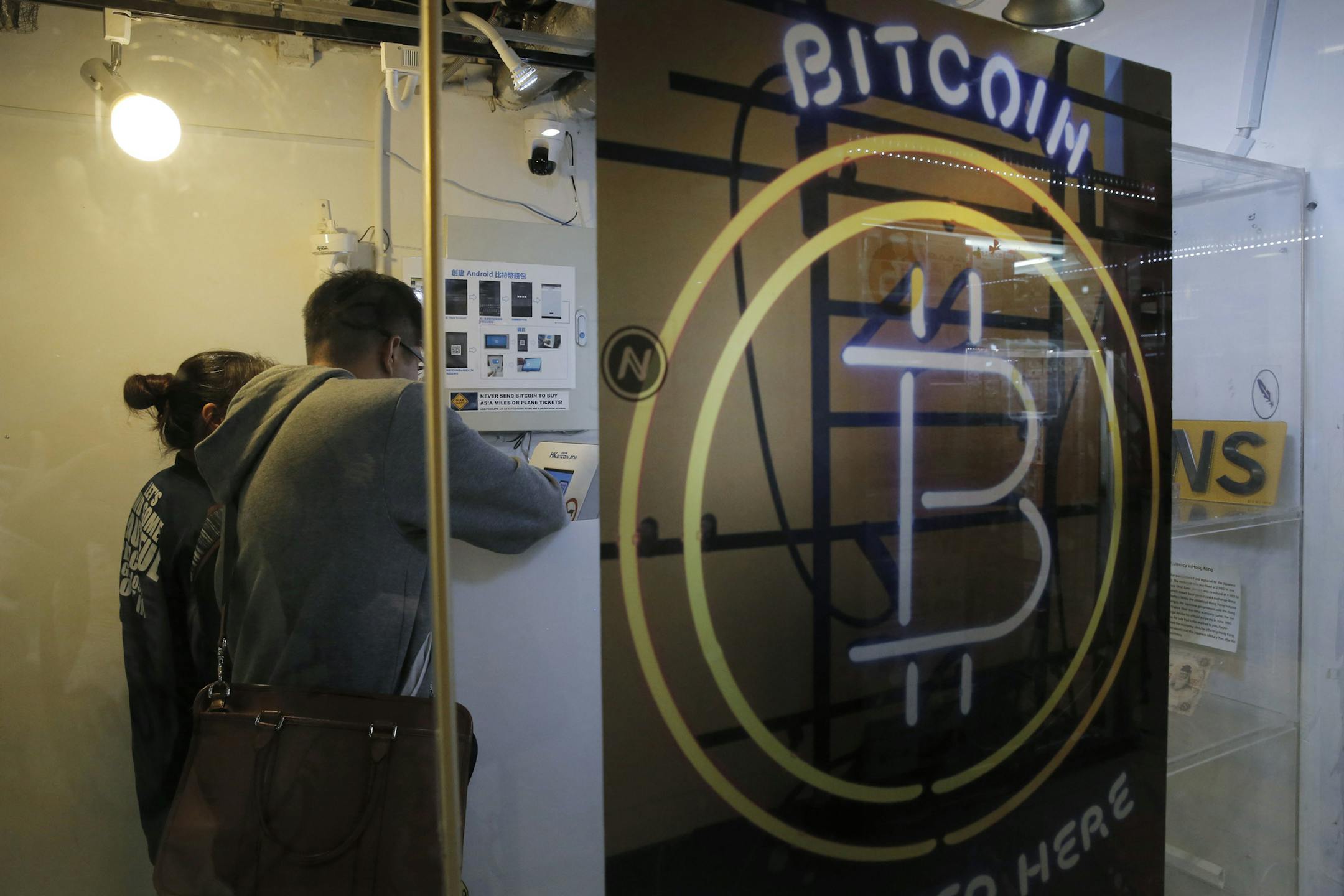 In this Friday, Dec. 8, 2017, photo, people use the Bitcoin ATM in Hong Kong. The launch of a U.S. futures contract for bitcoin on Sunday, Dec. 10, 2017, underscores the virtual currency's increasing mainstream acceptance, including in many parts of Asia, where it already has a wide following among speculators and investors. (AP Photo/Kin Cheung)