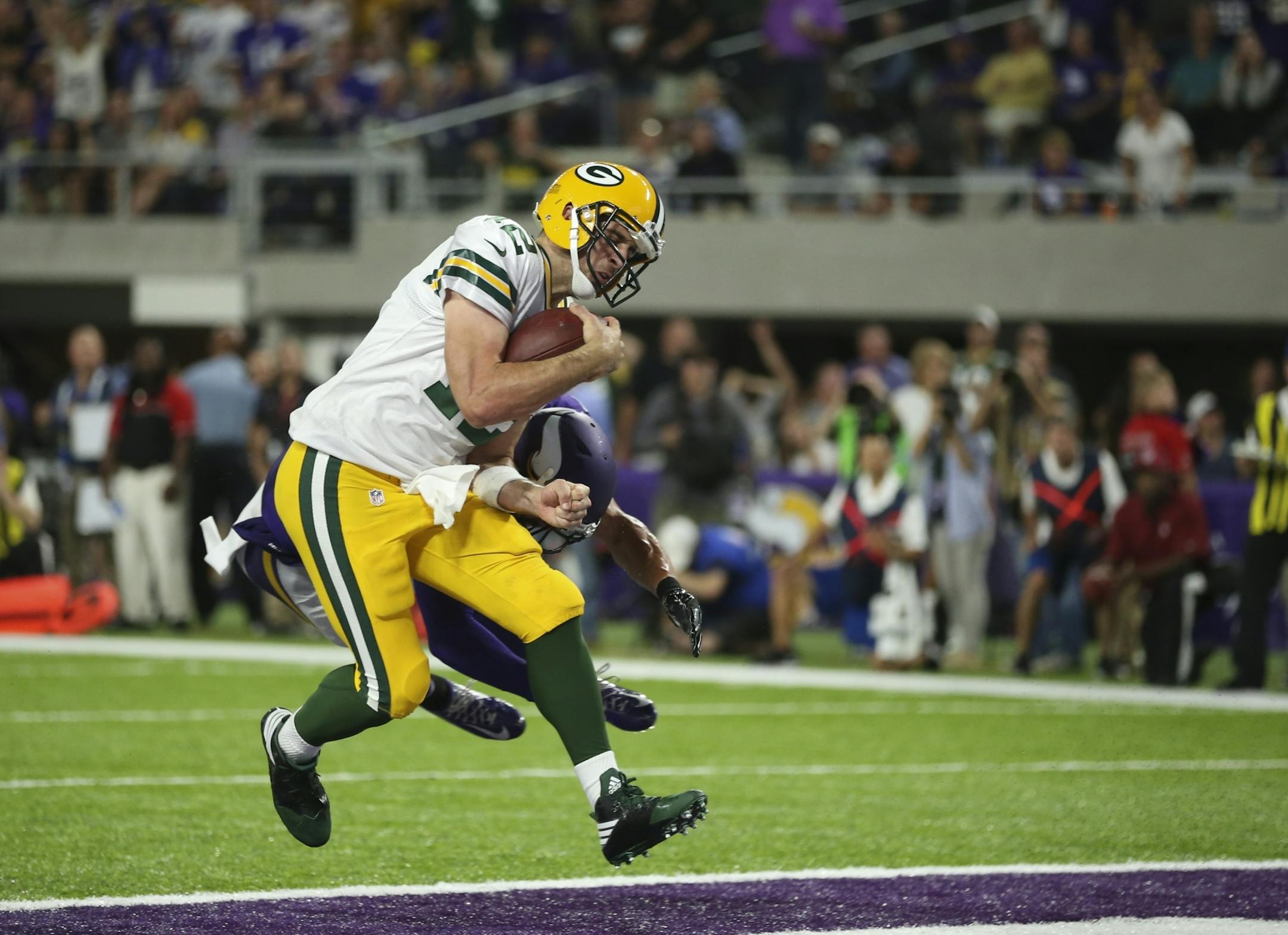 Vikings strong safety Andrew Sendejo (34) hit Green Bay Packers quarterback Aaron Rodgers (12) hard in the end zone after his fourth quarter touchdown brought the Packers to within three points of the Vikings.