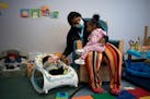 Rasheena Bickham, parent and program manager at the Northside Child Development Center in Minneapolis, read to Kasai Anderson, left, 5 months, and Ju