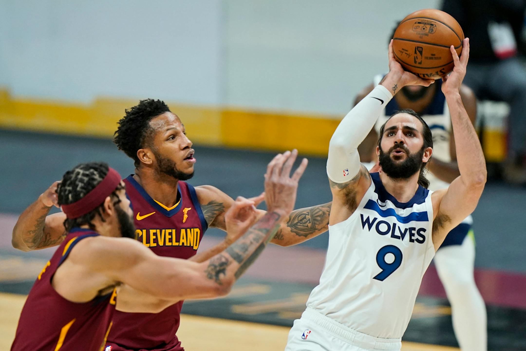 Minnesota Timberwolves' Ricky Rubio, right, shoots against Cleveland Cavaliers' JaVale McGee, left, and Lamar Stevens, center, in the second half of an NBA basketball game, Monday, Feb. 1, 2021, in Cleveland. (AP Photo/Tony Dejak)