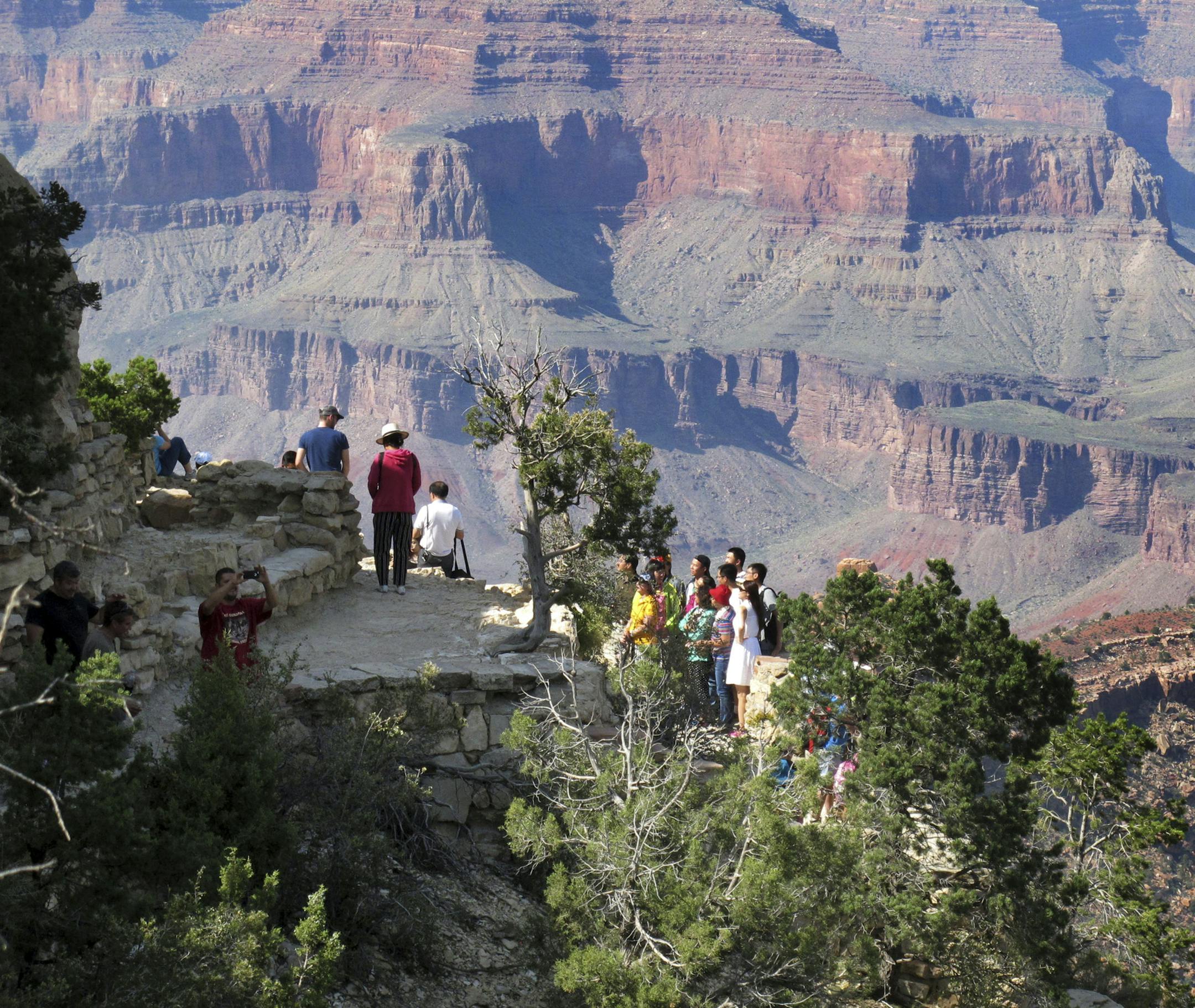FILE - In this Aug. 19, 2015, file photo, visitors gather at an outlook on the South Rim of Grand Canyon National Park in northern Arizona. Democratic senators are harshly criticizing a National Park Service plan to impose steep increases in entrance fees at 17 of its most popular parks, including the Grand Canyon, Yosemite, Yellowstone and Zion. (AP Photo/Felicia Fonseca, File)