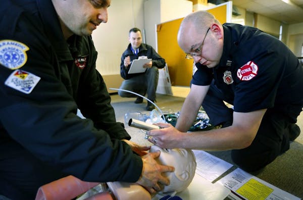 St. Paul firefighter paramedics Mark Sottile (left) and Luke Ritchie (right), practice rapid sequence intubation while being observed by Aaron Burnett