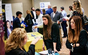 FILE — Attendees listen as potential employers talk about their companies during a job fair in Miami on Feb. 20, 2024. On average, economists expect