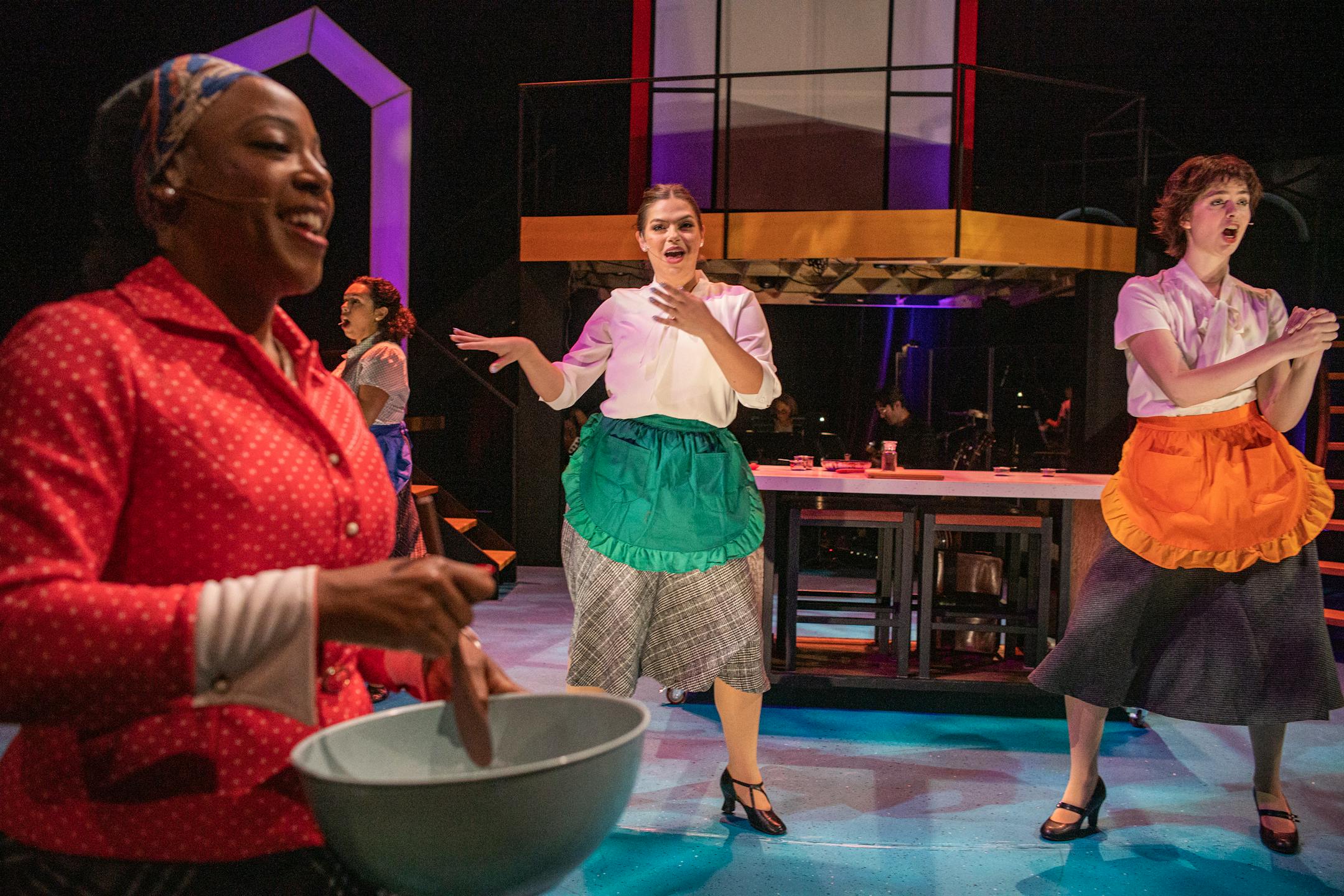 Lynnea Doublette, passes by as Camryn Buelow and Olivia Kemp dance off in the Hamburger Helper scene in St. Paul, Minn., on Sunday, Nov. 19, 2023. For a century, Betty Crocker has been an icon of womanhood, motherhood, and home. "I am Betty," a new musical, explores the General Mill's corporate spokesmodel that began as a signature on letters then became a homemaker dishing out recipes before becoming, in contemporary times, a spoon. ] RICHARD TSONG-TAATARII • richard.tsong-taatarii @startribune.com