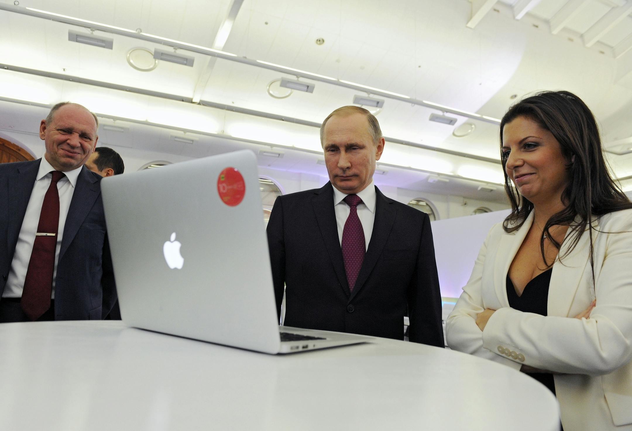 FILE - In this Thursday, Dec. 10, 2015 file photo, Margarita Simonyan, the editor-in-chief of state-funded RT television network, right, Russian President Vladimir Putin, center, and Kremlin's first deputy chief of staff, Alexei Gromov, left, attend an exhibition marking RT's 10th anniversary in Moscow, Russia. Russian lawmakers warned Thursday, Oct. 5, 2017 that Moscow could retaliate if the U.S. moves to impose restrictions on Russia's state-funded RT television network and Sputnik news agency