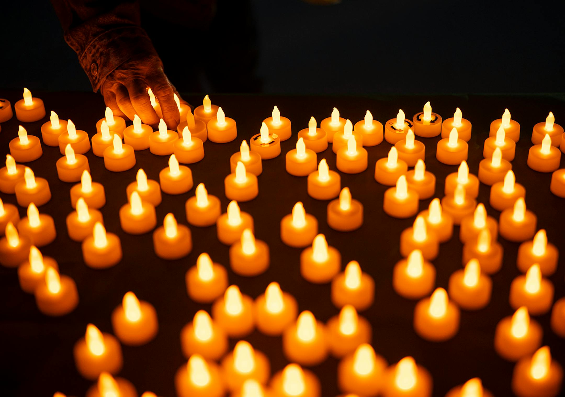 People picked up electric votive candles from a table before the program began.