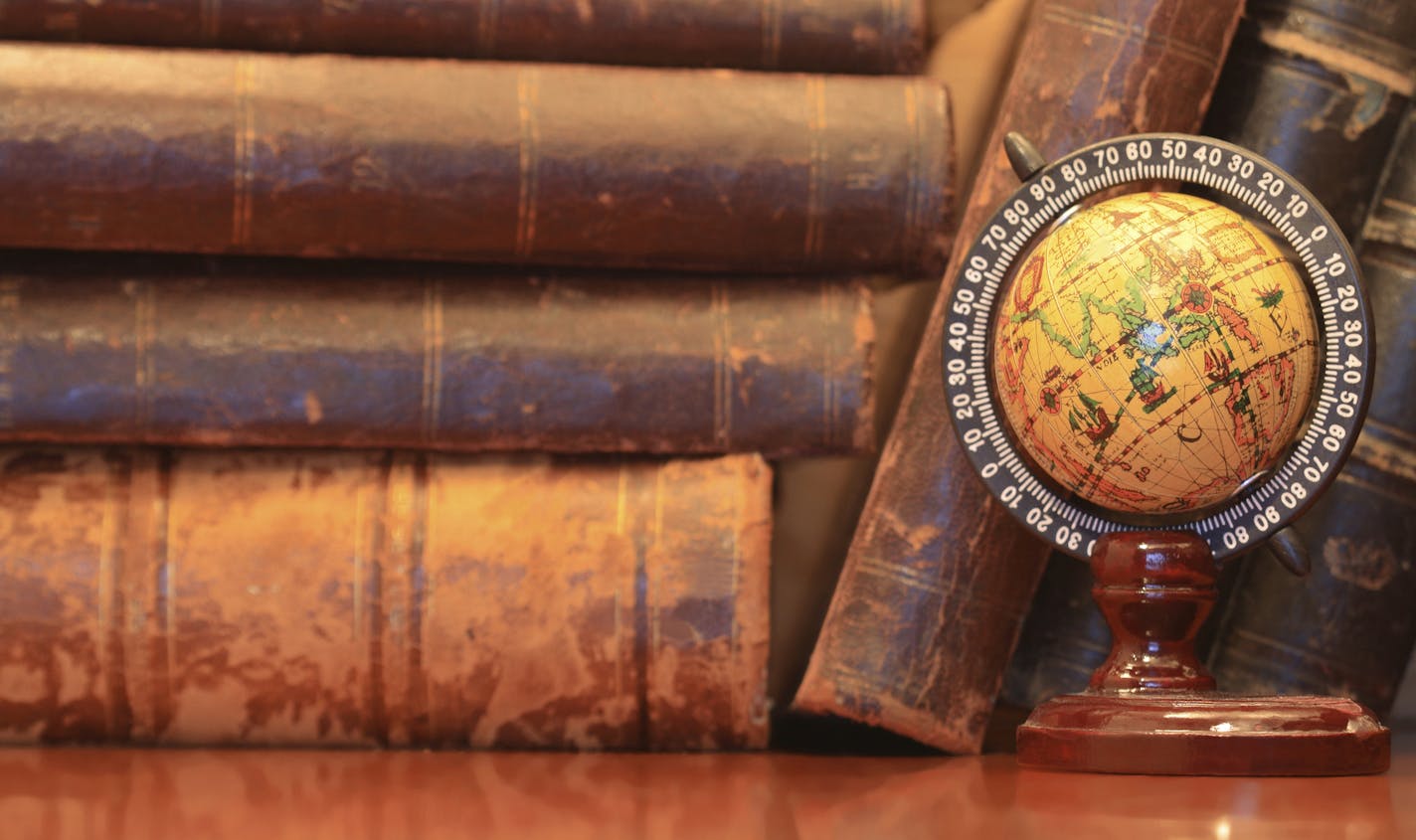 Vintage still life with stack of old books and globe on wooden table by Konstantin Kirillov