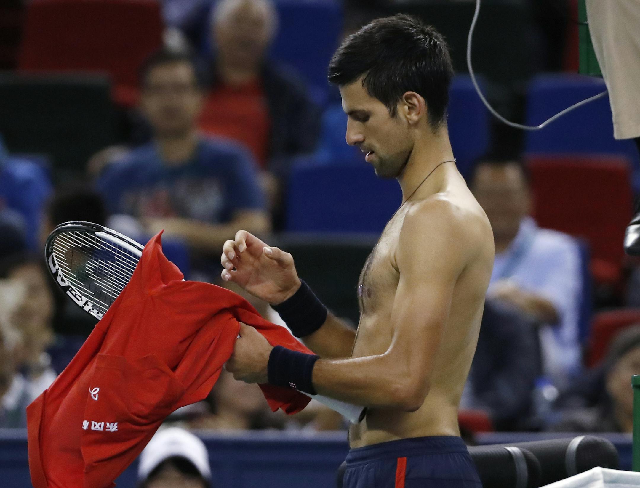 Novak Djokovic of Serbia changes his shirt after losing a point to Roberto Bautista Agut of Spain during the men's singles semifinals match of the Shanghai Masters tennis tournament at Qizhong Forest Sports City Tennis Center in Shanghai, China, Saturday, Oct. 15, 2016. (AP Photo/Andy Wong)