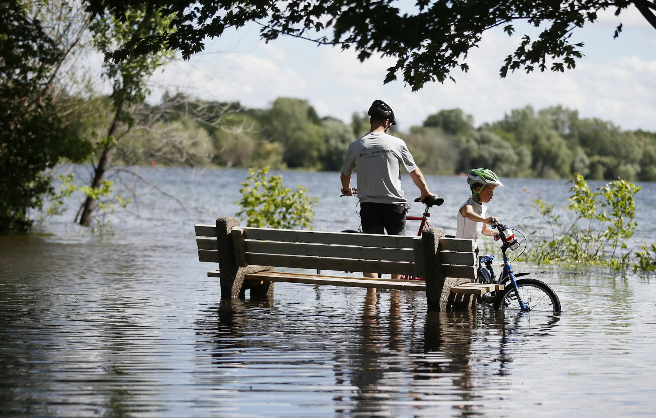 Bicycling around Lake Nokomis on Sunday, Brian Benke and his 8-year-old son, Luca, braved the flooded sidewalks left from Saturday’s storms.