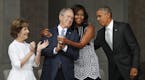 First lady Michelle Obama, center, hugs former President George W. Bush, as President Barack Obama and former first lady Laura Bush walk on stage at t