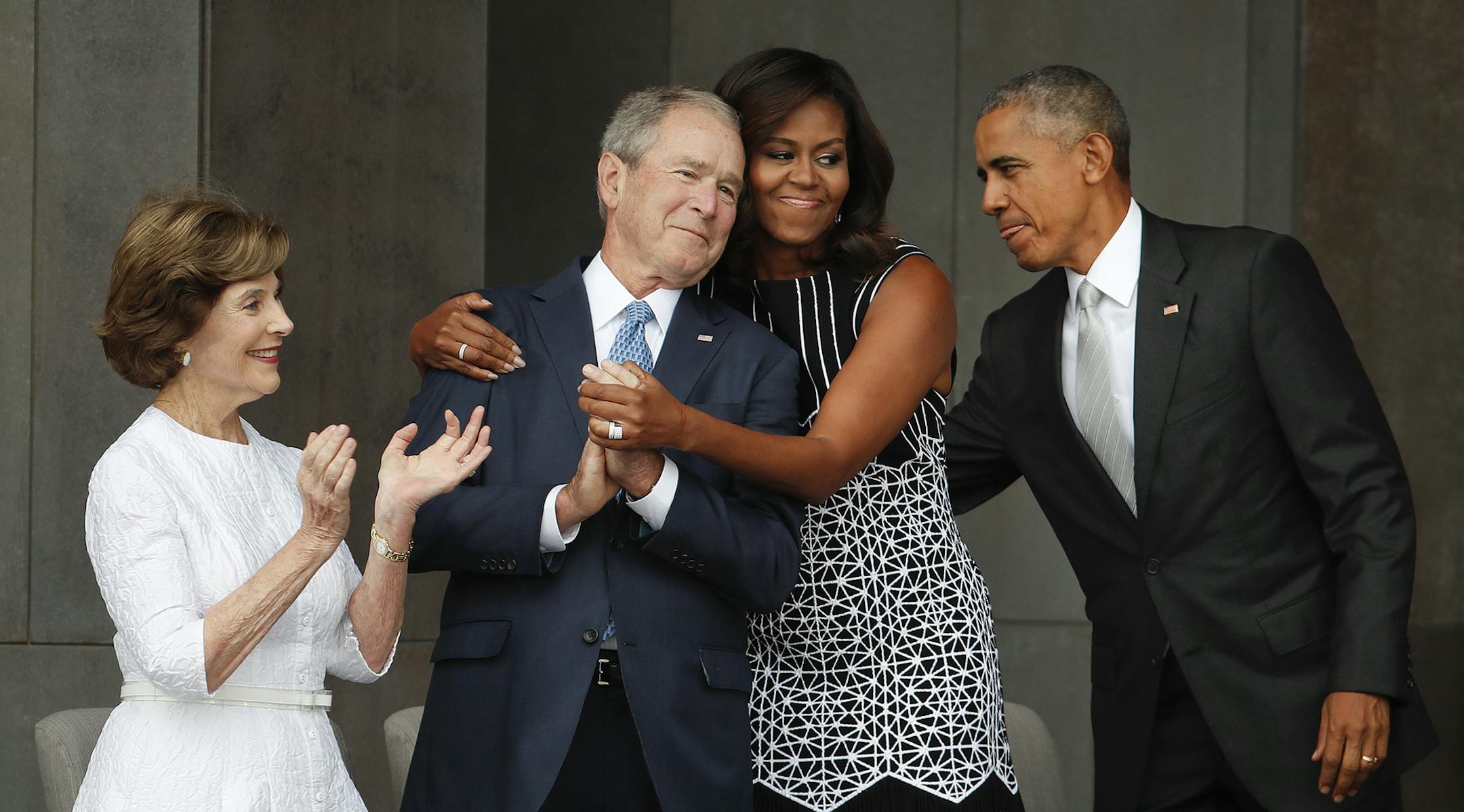 First lady Michelle Obama, center, hugs former President George W. Bush, as President Barack Obama and former first lady Laura Bush walk on stage at the dedication ceremony of the Smithsonian Museum of African American History and Culture on the National Mall in Washington, Saturday, Sept. 24, 2016. (AP Photo/Pablo Martinez Monsivais) ORG XMIT: MIN2016092611012508
