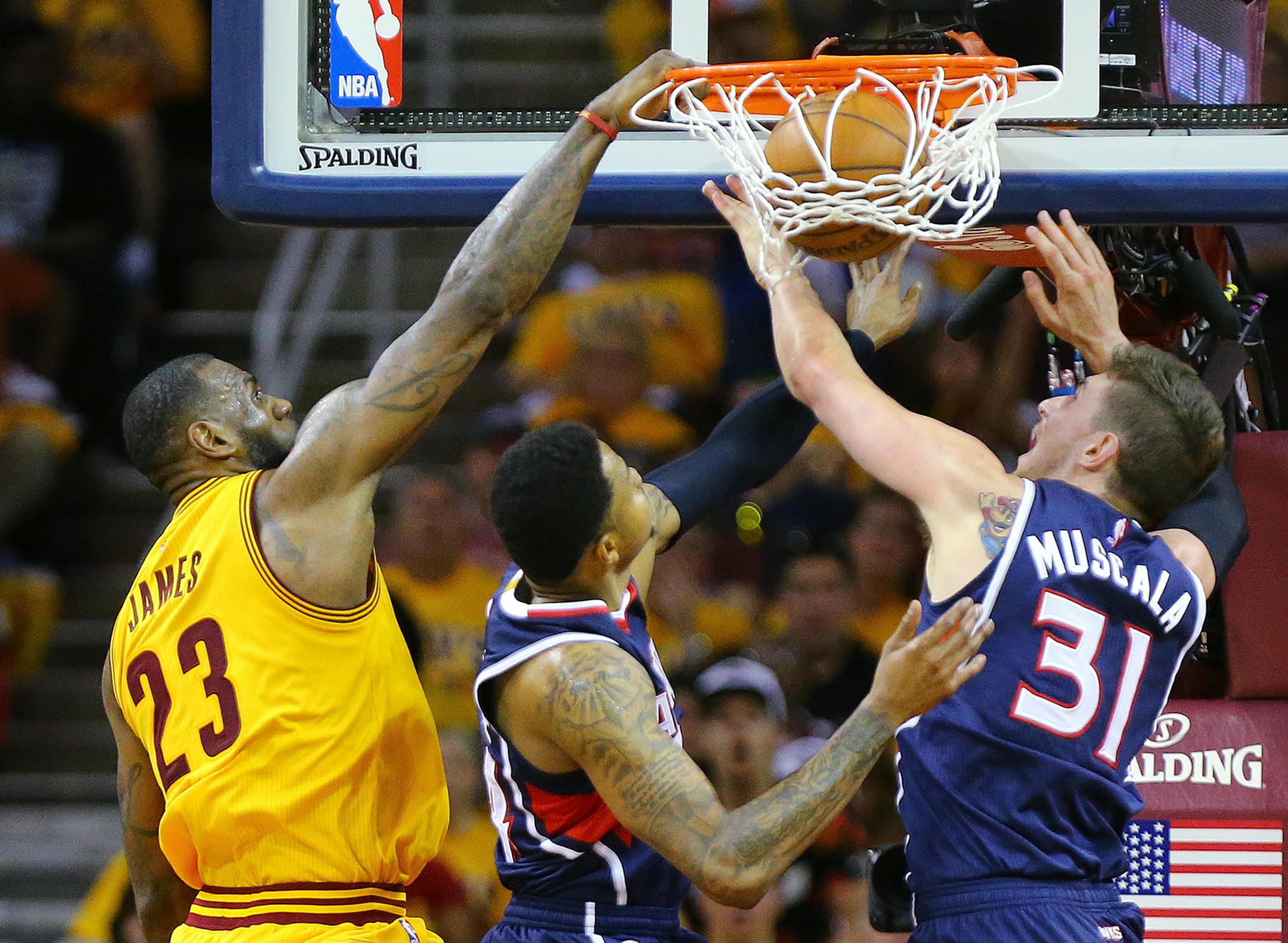 Cleveland's LeBron James, left, dunks against Atlanta defenders Kent Bazemore, center, and Mike Muscala, right, in the Eastern Conference Finals on Sunday, May 24, 2015, in Cleveland. (Curtis Comptom/Atlanta Journal-Constitution via AP)