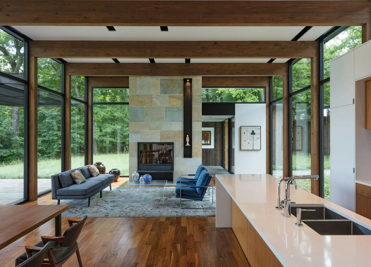 The see-through house is composed of glass walls juxtaposed with warm walnut floors and a bluestone fireplace.