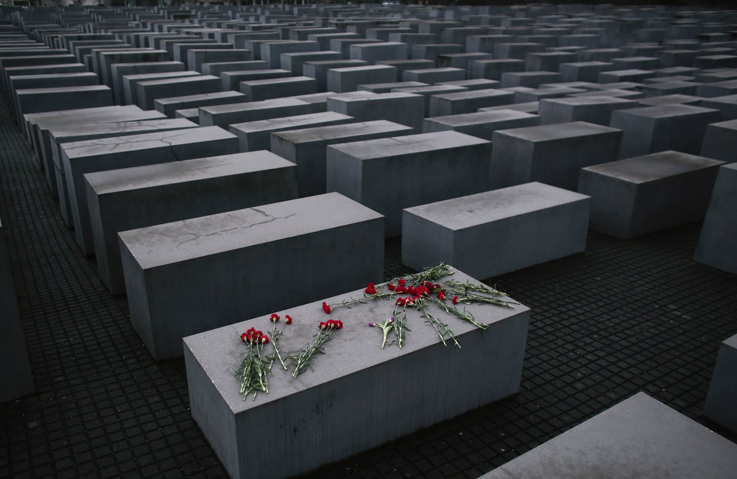 In this Tuesday, Jan. 27, 2015 file photo, flowers lay on a concrete slab of the Holocaust Memorial to mark the International Holocaust Remembrance Day in Berlin. One of Germany's richest families, the Reimann family, which owns Krispy Kreme Doughnuts, Pret A Manger, Peet's Coffee and other famous international brands is giving millions to support Holocaust survivors. The family has established the Alfred Landecker Foundation in Germany to oversee the efforts, named after a German Jew who was ki