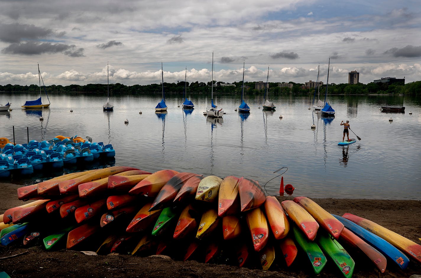 A woman paddle boarded near he rental site on Lake Bde Maka Ska as people walked around the lake on Memorial Day.