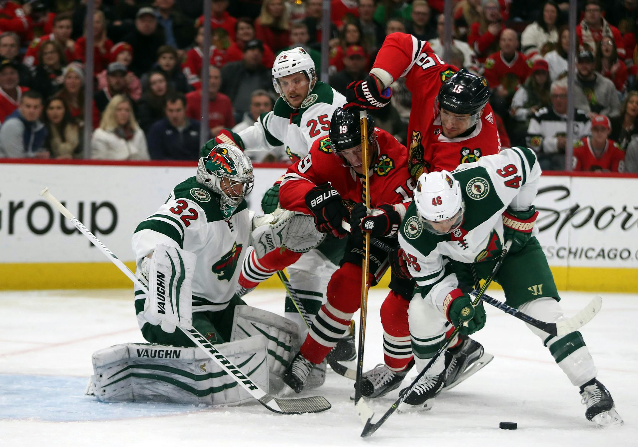 Blackhawks center Jonathan Toews (19) and Artem Anisimov (15) can't get to a puck in front of Wild goalie Alex Stalock (32) and defenseman Jared Spurgeon (46) .