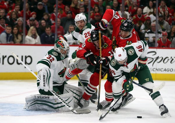 Blackhawks center Jonathan Toews (19) and Artem Anisimov (15) can't get to a puck in front of Wild goalie Alex Stalock (32) and defenseman Jared Spurg