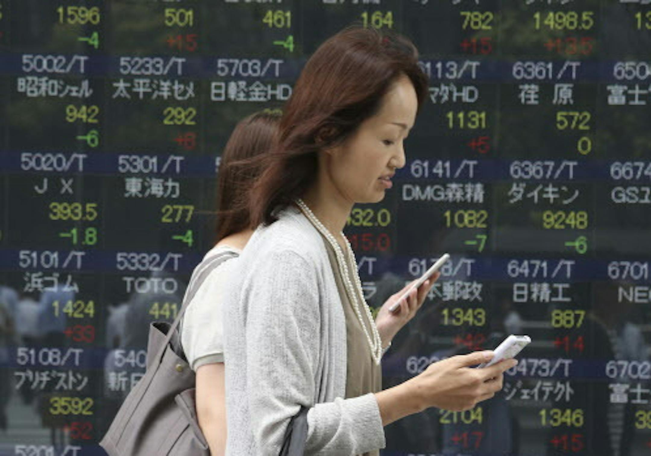 People walk by an electronic stock board of a securities firm in Tokyo, Monday, July 25, 2016. Asian shares were mostly higher Monday, cheered by upbeat signs from Wall Street, a strengthening U.S. dollar and promises from the Group of 20 nations over the weekend to support global growth. (AP Photo/Koji Sasahara)