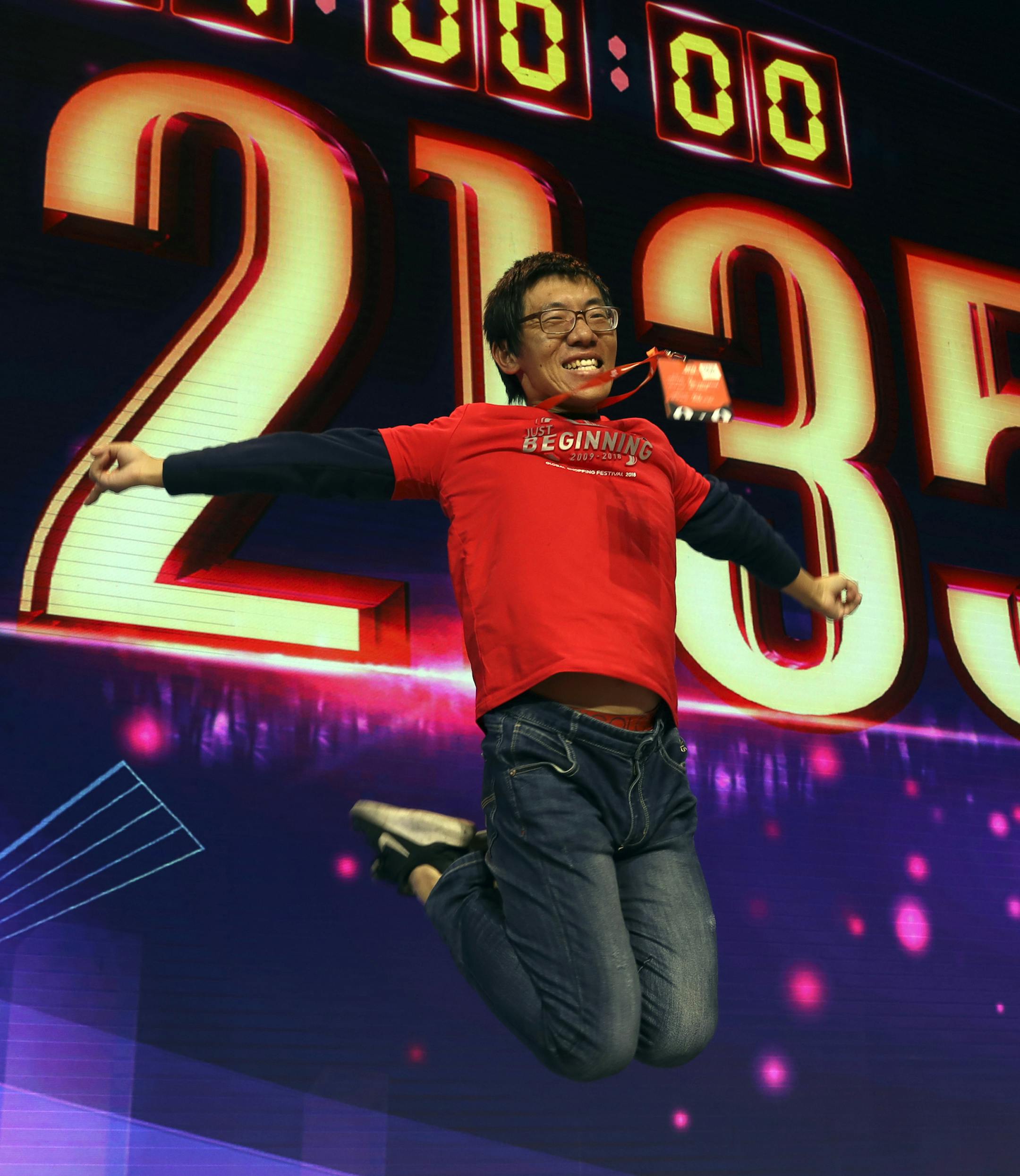 A staff member jumps for a photo to celebrate after Alibaba's 11.11 Global Shopping Festival also known as Singles Day sets a new record of RMB213.5 billion or more than US$30 billion in Shanghai, China, Monday, Nov. 12, 2018. Online shoppers in China have shattered last year's record of $24 billion in sales on the country's annual buying frenzy Sunday, as the tradition marked its 10th year. (AP Photo/Ng Han Guan) ORG XMIT: XHG118