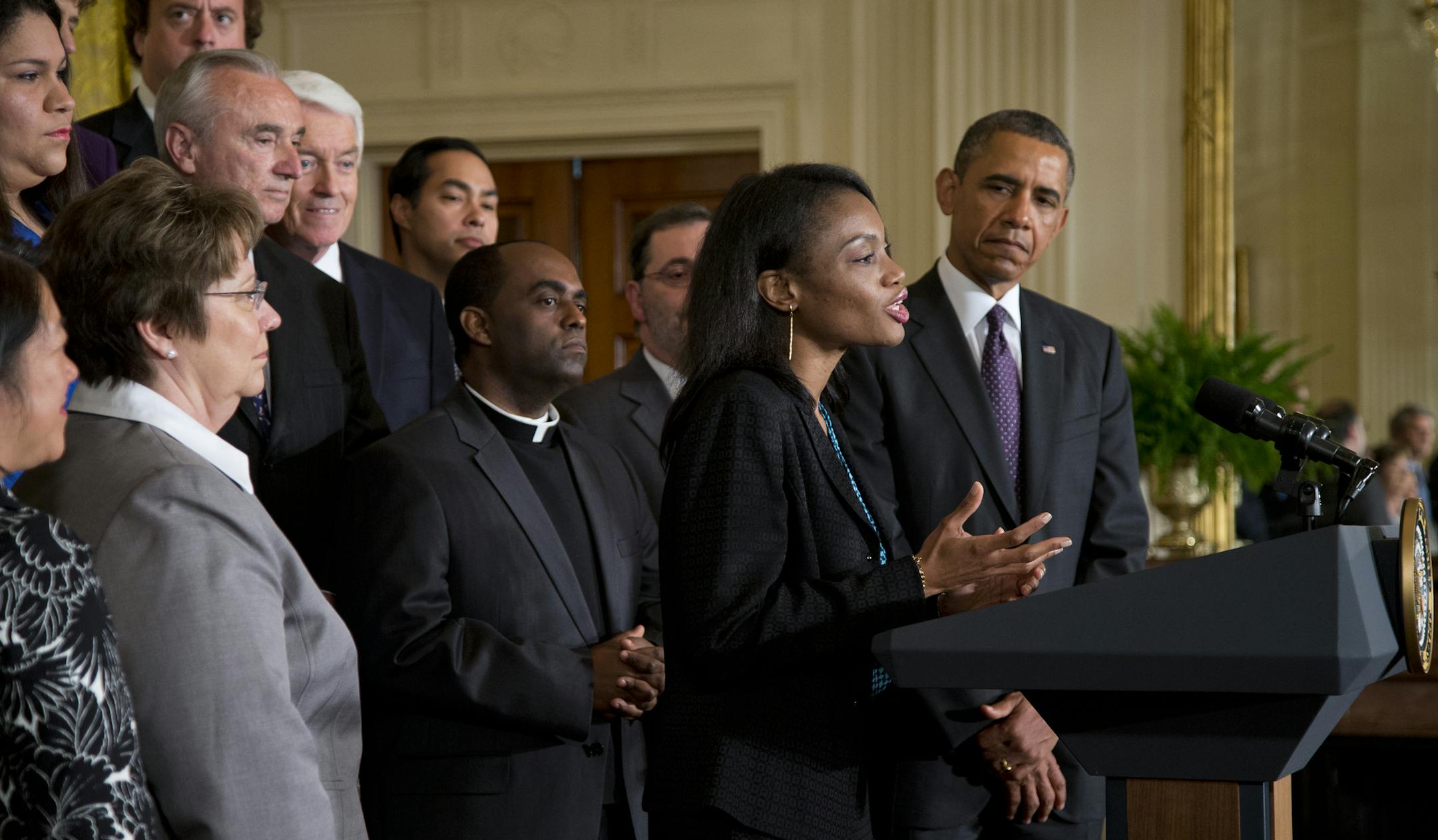 President Barack Obama, right, looks on as Tolu Olubunmi, a immigration activist, speaks during remarks on immigration reform in the East Room of the White House on Tuesday, June 11, 2013, in Washington. The Senate is preparing to cast the first votes on a landmark bill that offers the best chance in decades to remake the nation's immigration system and offer eventual citizenship to millions. (AP Photo/Evan Vucci)
