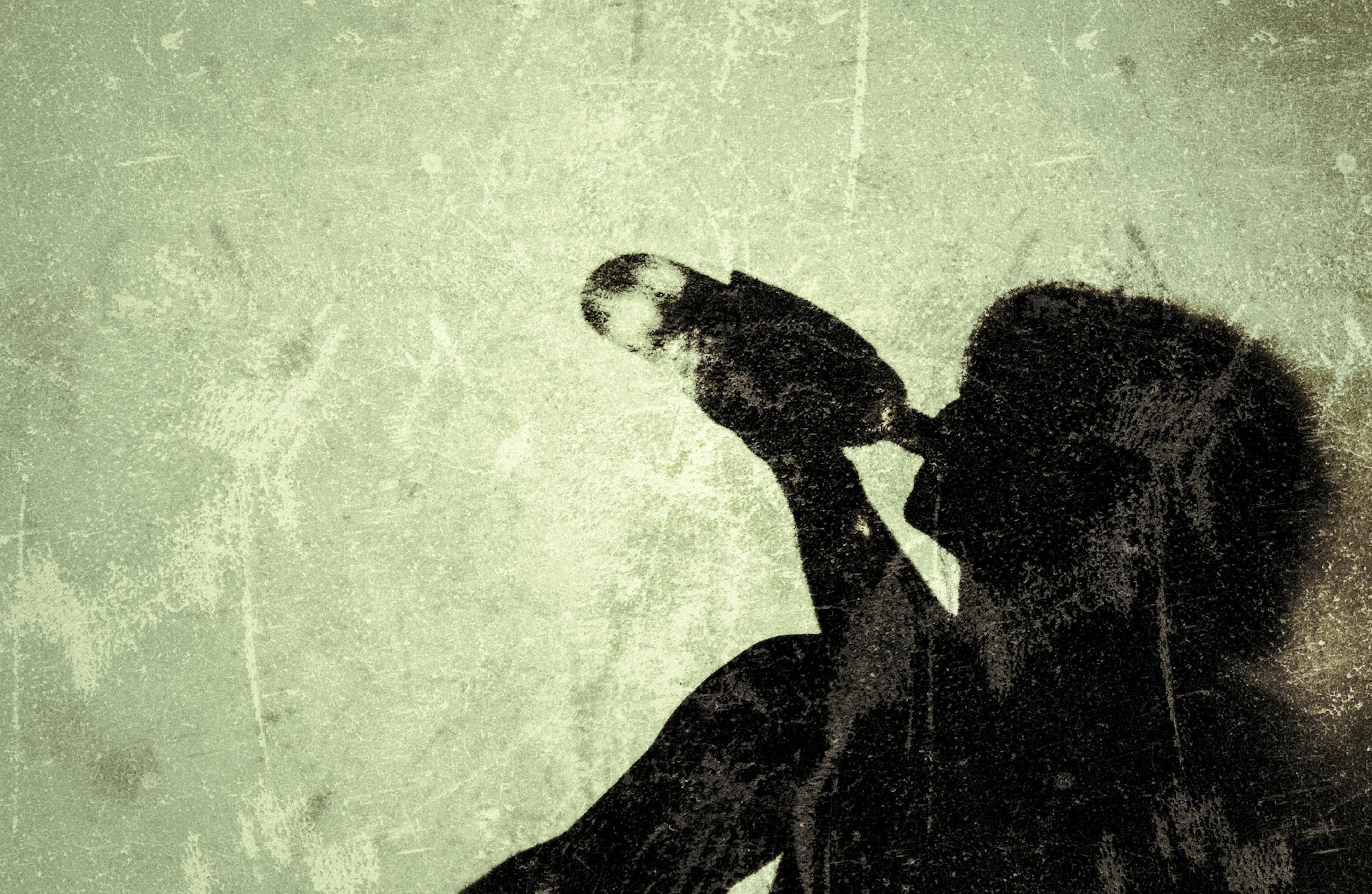 Shadow of an alcoholic woman drinking directly from the bottle.
