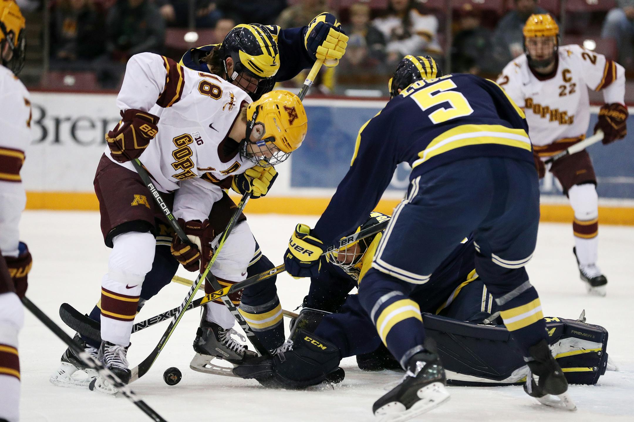 Minnesota's Leon Bristedt (18) tries to get the puck past Michigan goaltender Hayden Lavigne (30) and defenseman Luke Martin (2) in the first period on Friday