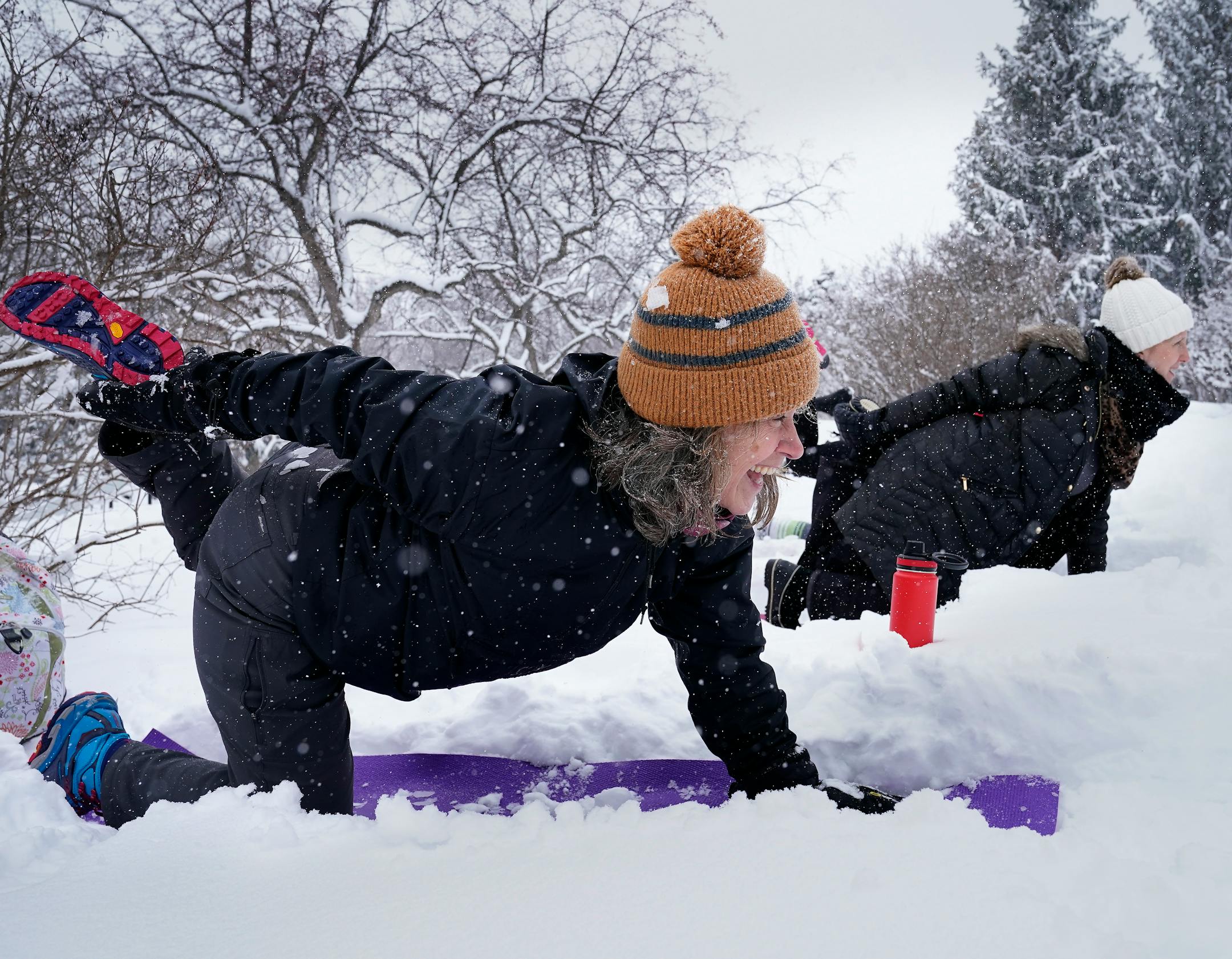 Snowga participant Liz Kelliher is partially buried in snow while striking a pose.