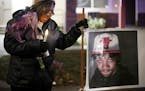 Irma Burns, the mother of Jamar Clark, leans on a sign bearing a photo of her son during a 2017 vigil on the two-year anniversary of his death.