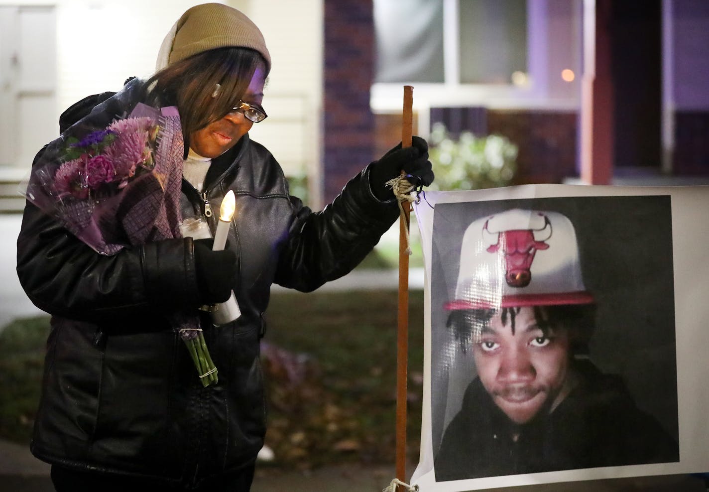 Irma Burns, the mother of Jamar Clark, leans on a sign bearing a photo of her son during a 2017 vigil on the two-year anniversary of his death.