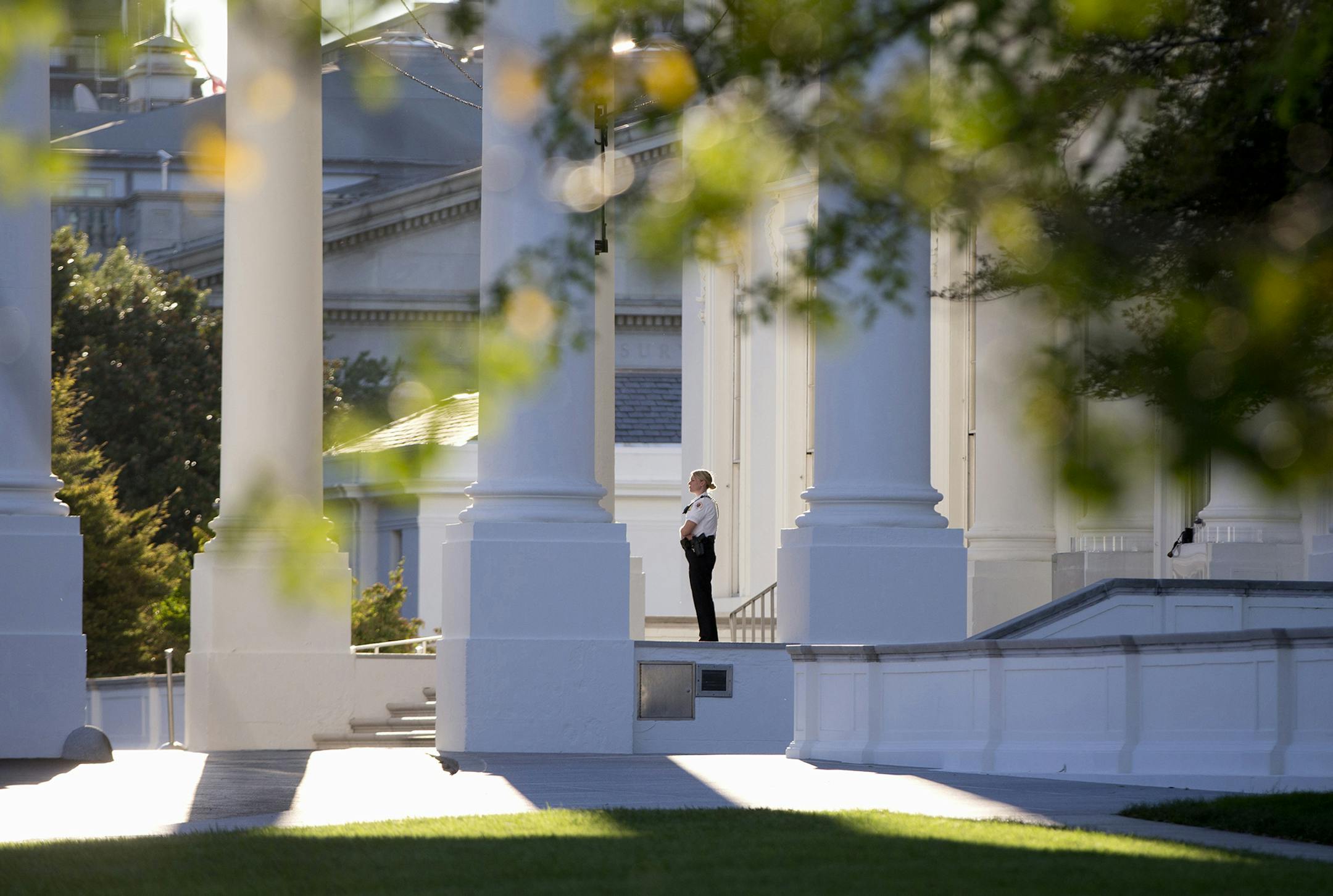 FILE - In this Sept. 22, 2014 file photo, a member of the Secret Service Uniformed Division looks out from the North Portico of the White House in Washington. Secret Service Director Julia Pierson said Tuesday the front door to the White House now locks automatically in a security breach. Pierson told a House panel that the switch to automatic locks at the White House's north door was made after an Army veteran jumped the fence on Sept. 19 and made his way into the interior of the building throu