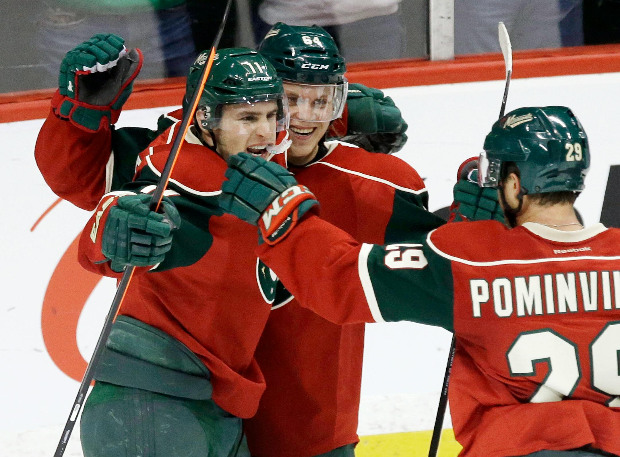 Minnesota Wild's Zach Parise, left, celebrates his goal off Calgary Flames goalie Reto Berra with Mikael Granlund, center, of Finland and Jason Pominville in the third period of an NHL hockey game, Monday, March 3, 2014, in St. Paul, Minn. The Wild won 3-2. (AP Photo/Jim Mone)