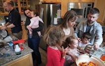 Sean Boley washes dishes as Betsy Ohrn holds daughter Esme, 1, while spouse Tye Schulke and their son Axel, 3, help Sara Kemper and daughters Ivy, 4, 