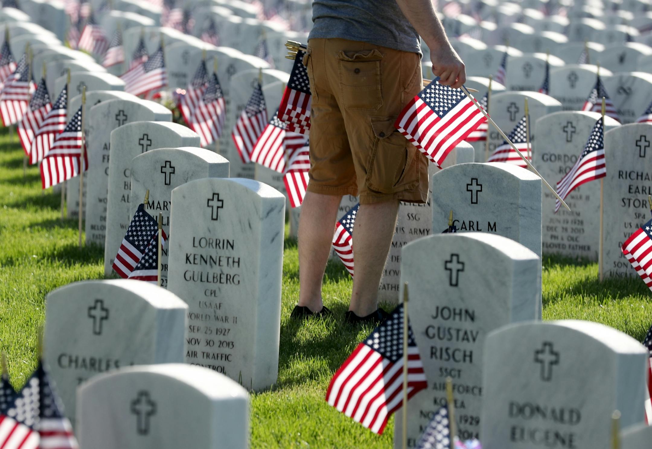 A volunteer planted American flags Saturday on the graves of soldiers for Memorial Day at Fort Snelling National Cemetery.