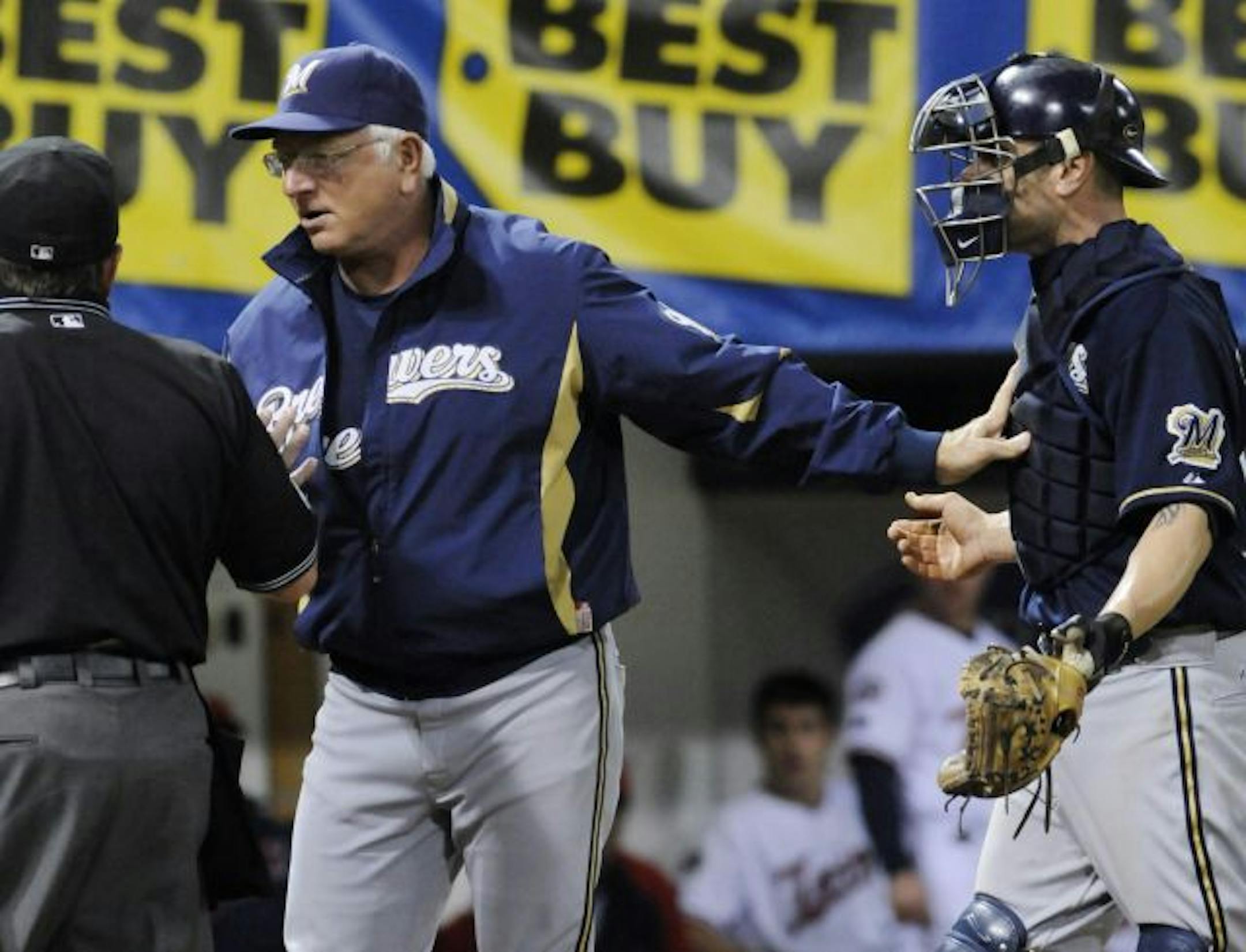 Milwaukee Brewers manager Ken Macha, center, keeps catcher Jason Kendal, right, away from plate umpire Charlie Reliford, left, after he warned Brewers pitcher Braden Looper (not shown) after Minnesota Twins' Justin Morneau was hit by a fifth-inning pitch in a baseball game Saturday, May 23, 2009, in Minneapolis.
